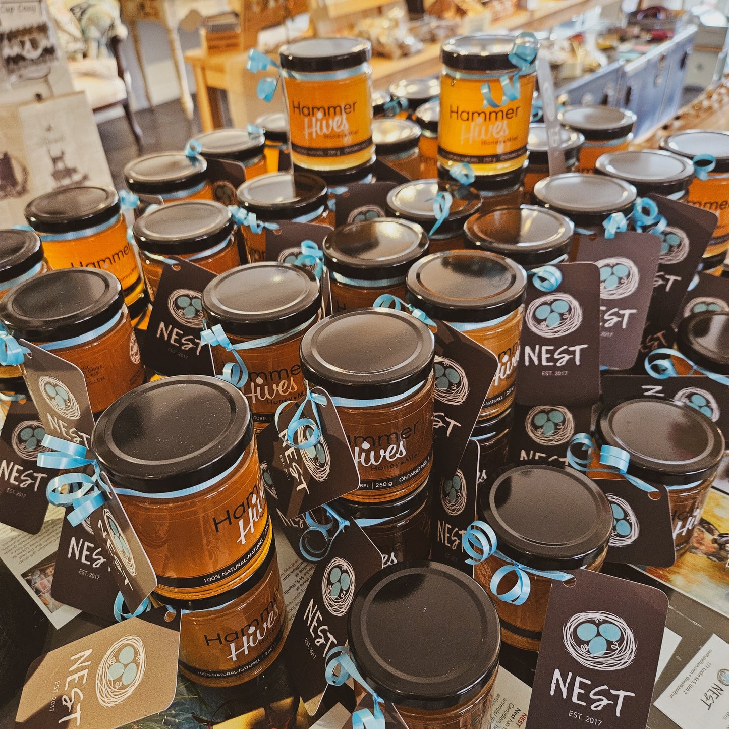 Rows of stacked jars of Hammer Hives honey with Nest cards on a ribbon