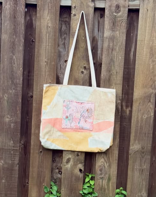 Tote bag with a colorful design hanging on a wooden fence
