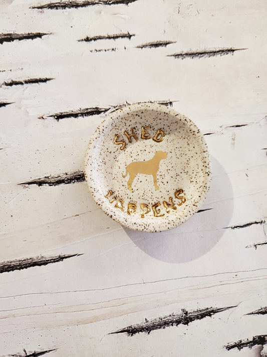 Small trinket dish with gold dog detail saying Shed Happens on birchbark background